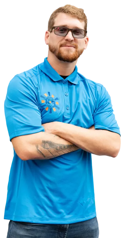 A man in a blue company polo shirt posing with his arms crossed against a light background.