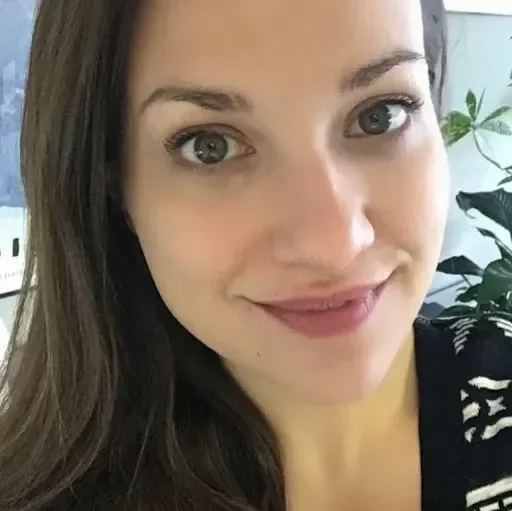 A close-up portrait of a smiling woman with dark hair.